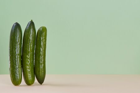 Smooth ripe cucumber standing on beige table. Healthy vegetable. Diet nutrition concept. Copy space. Green backgroundの写真素材