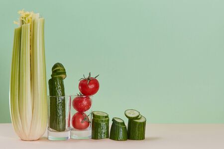 Healthy lifestyle. Celery, cucumber and tomato in glass. Eco-friendly food. Diet. Copy space. Pastel green backgroundの写真素材