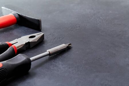Hammer, pliers and screwdriver on dark background. Tools for repair, copy space. Labour day....