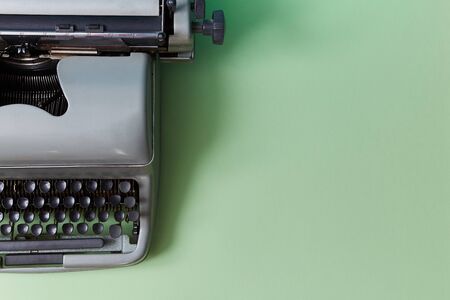 Retro typewriter on green background. Authorship. Journalism. Manual machine with keys for typewriting, copy spaceの写真素材
