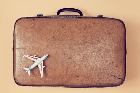 Travelling by plane. Travel background. Grandparents trip. Vintage shabby suitcase and model of airplane, copy space.の写真素材