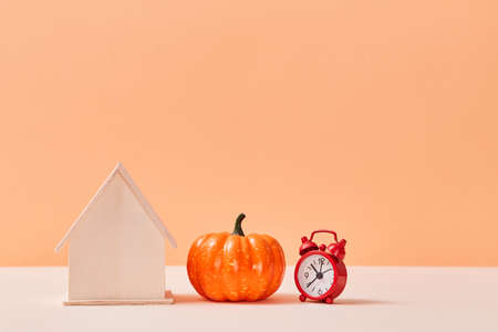 Happy thanksgiving day. Harvest festival. Time to celebration. Red alarm-clock, house miniature and pumpkin. Copy spaceの写真素材