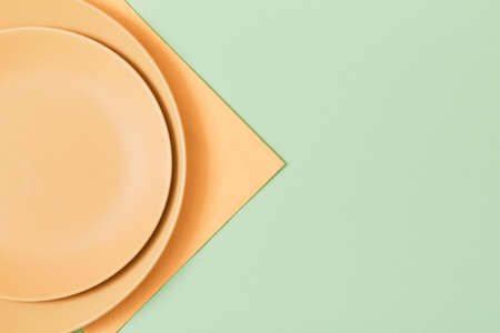Festive dinner. Festive table setting. Holiday celebration. Empty beige plate and napkin, isolated on green. Copy spaceの写真素材