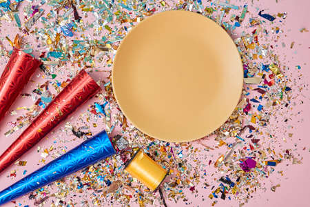 Happy celebration. Party decoration. Celebrating event. Plate and reel of yellow ribbon. Colourful confetti on pinkの写真素材