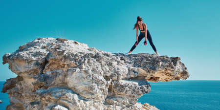 Fitness. Rock climbing. Sport. Woman on top of cliff. Active and fit female train outdoors. Ocean...