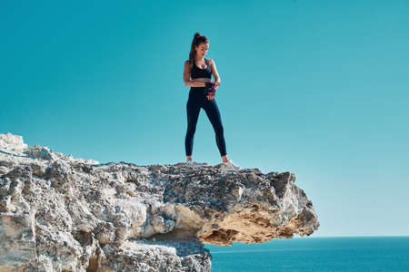 Active and fit female train outdoors. Ocean landscape. Fresh air. Rock climbing. Sport. Woman on top of cliff.の写真素材