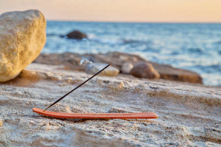 Spa composition. Aromatherapy. Spa and wellness. Aroma stick and incense on seashore. Stones and sea on backgroundの写真素材