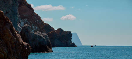 Nude beach. Crystal clean ocean water. Summer vibe. Virgin nature landscape. Boat floating on horizon. Cloudless skyの写真素材