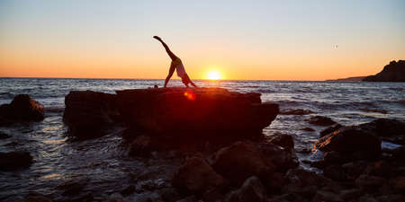 Slim lady performing training on fresh air. Cute sunset time. Outdoors and active lifestyle. Yoga and pilates conceptの写真素材