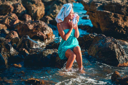 Lady enjoying seascape sitting on rock. Summer time and spa day. Virgin nature, beauty treatment and relaxation conceptの写真素材