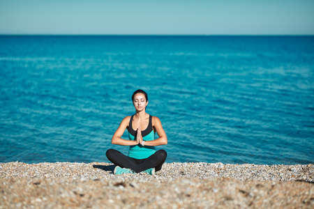 Meditation sitting on warm beach rocks. Stunning nature view and fresh air. Yoga time and healthy lifestyle conceptの写真素材