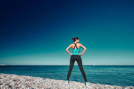 Female having workout on coastline. Fresh air and blue cloudless sky. Active lifestyle and fitness...
