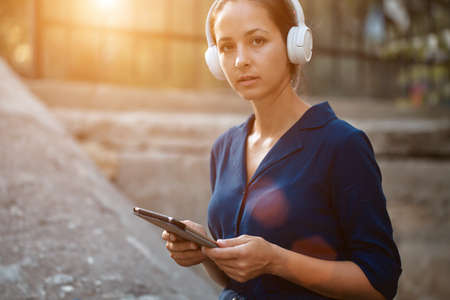 Pretty woman holding tablet and wearing headset. Study while travel idea. Studentship and distance learning conceptの写真素材