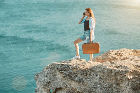 Young woman on holiday taking picture to memory. Lady with vintage suitcase. Summer time and vacation abroad conceptの写真素材