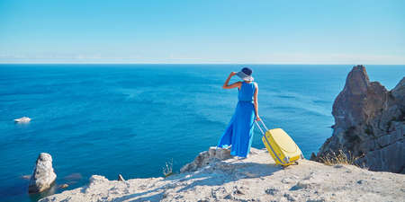 Lady arrived on holiday with yellow suitcase. Sunny weather and warm ocean. Vacation and travelling...