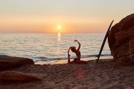 Yogi woman practicing yoga on seashore. Meditation idea. One Legged King Pigeon exercise. Eka Pada Rajakapotasana pose.の写真素材