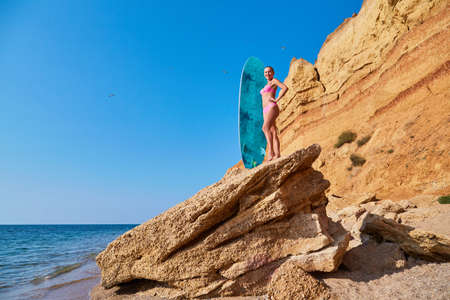 Summer time, beach day, holiday trip, surfing idea, copy space. Woman on cliff sunbathing, hot...