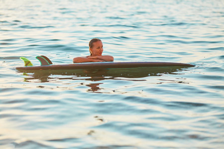 Lady swim in water, calm ocean. Girl with surfboard on vacation. Idea of summer time, time to rest,...