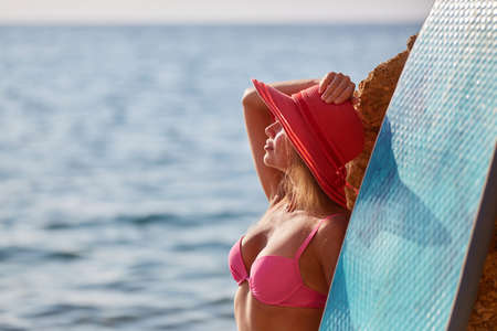 Young woman enjoy sunny weather on beach. Summer time and surfing sport idea. Time to relax and holiday trip conceptの写真素材