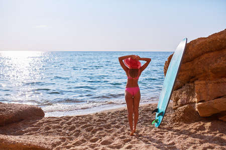 Woman standing with back watching seascape. Ocean and sandy beach. Surf, summer time and holiday trip idea, copy spaceの写真素材