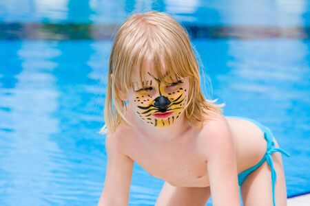 Girl with paint on his face in the poolの写真素材