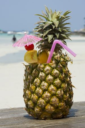 Tropical pineapple cocktail drink at the beach overlooking the oceanの写真素材