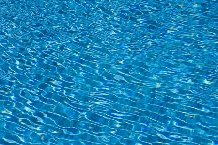 Sun reflection on the blue clear water ripples of swimming pool with mosaic bottomの写真素材