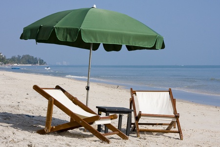 Wooden beach chairs under umbrella.の写真素材