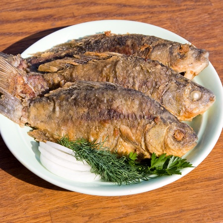 Fried fish crucian in plate on wooden tableの写真素材