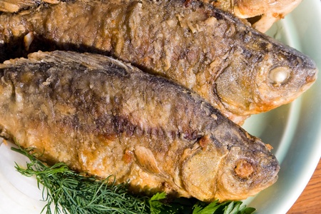Fried fish carp in plate on wooden tableの写真素材