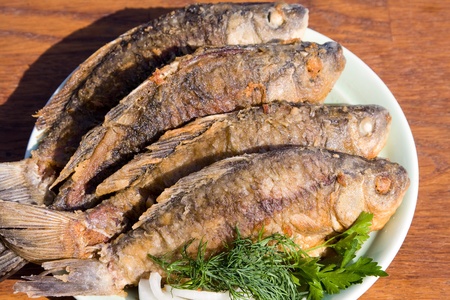 Fried fish carp in plate on wooden tableの写真素材