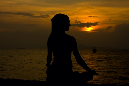 Healthy woman doing yoga outdoor, sunset over seaの写真素材