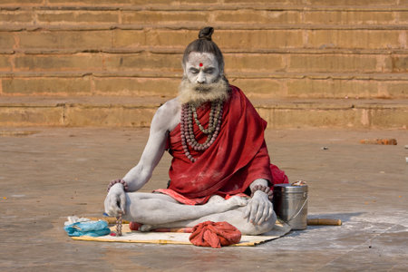 VARANASI, INDIA - December 1: An unidentified naga baba sadhu sits on the ghat along the Ganges on December 1, 2012 in Varanasi, India. Tourism has drawn many alleged fake sadhus to Varanasiのeditorial素材
