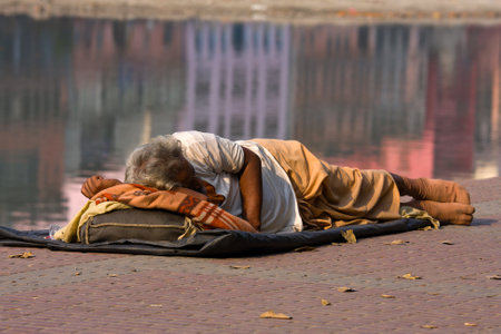 HARIDWAR, INDIA - NOV 8: An unidentified homeless man sleeps on the sidewalk near the River Ganges on November 8, 2012 in Haridwar, India. Poor Indians flock to Haridwar for charity.のeditorial素材