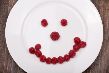 Fun food for kids - face on a plate of raspberriesの写真素材