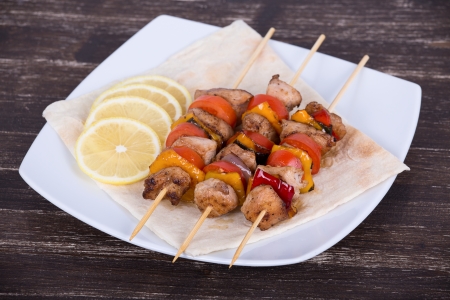 Tasty grilled meat and vegetables on skewer on plateの写真素材