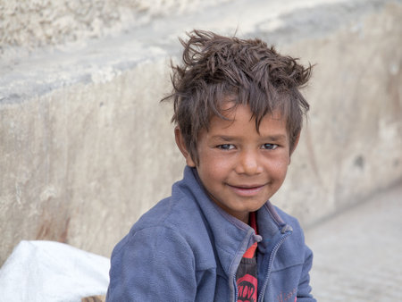 LEH, INDIA - SEPTEMBER 08 2014: An unidentified beggar boy begs for money from a passerby in Leh. Poverty is a major issue in Indiaのeditorial素材