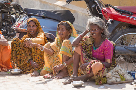 PUSHKAR, INDIA - OCTOBER 28, 2014:Unknown old indian beggars waits for alms on a street on the along ghat the sacred Sarovar lake. Pushkar - famous worship place in Indiaのeditorial素材