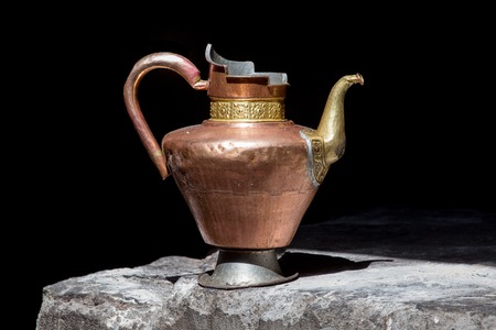 Old handmade tibetan pitcher on black background, close up. India,Ladakhの写真素材
