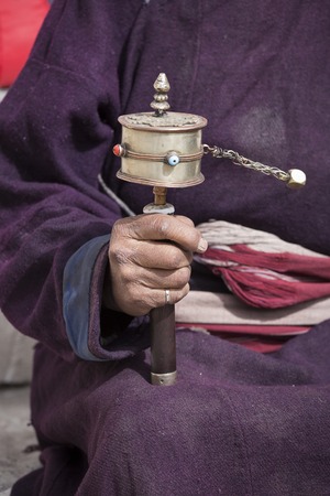 Old Tibetan man holding buddhist prayer wheel in Lamayuru Gompa, , Ladakh, India. Hand and prayer wheel, close upの写真素材