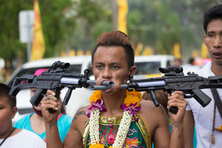 PHUKET, THAILAND - OCT 17, 2015: Chinese thai monk possessed by his god walks with his mouth pierced in Vegetarian Festival at Phuket Town. Festival is a famous annual also known as Nine Emperor Godsのeditorial素材