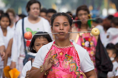 PHUKET, THAILAND - OCT 17, 2015: Chinese thai girl possessed by his god walks with his mouth pierced...