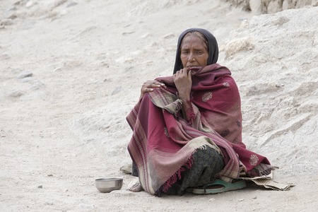 LEH, INDIA - JUNE 24, 2015: Unknown poor woman begs for money from a passerby on the street in Leh,...