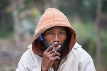 MRAUK-U, MYANMAR - JANUARY 27, 2016: Portrait of an unknown beggar who smokes a cigarette outdoorsのeditorial素材