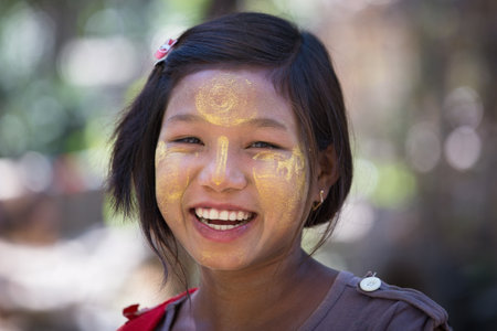 MRAUK-U, MYANMAR - JANUARY 27, 2016: Unidentified young Myanmar girl with thanaka on her smile face is happiness. Thanaka is a yellowish-white cosmetic paste made from ground bark.のeditorial素材