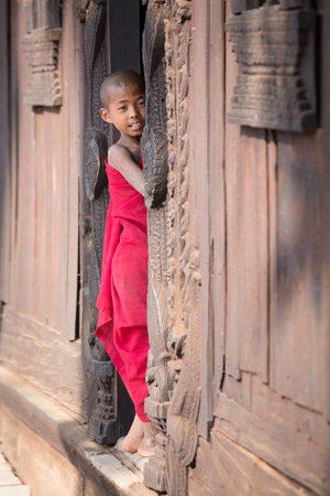 MANDALAY, MYANMAR - JANUARY 17, 2016 : Young monk standing and looking at Shwenandaw Monastery is built in the traditional Burmese architectural styleのeditorial素材