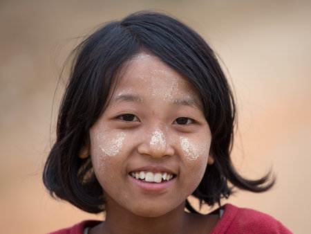 MRAUK-U, MYANMAR - JANUARY 28, 2016 : Unidentified young Myanmar girl with thanaka on her smile face is happiness. Thanaka is a yellowish-white cosmetic paste made from ground bark.のeditorial素材