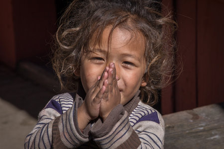 MANANG VILLAGE, WESTERN NEPAL - OCTOBER 14, 2016 : Portrait young girl with folded hands in street . Close upのeditorial素材