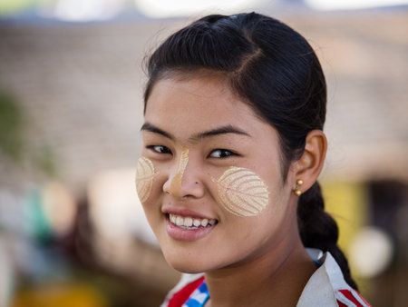 MANDALAY, MYANMAR - JANUARY 17, 2016: Unidentified young Myanmar girl with thanaka on her smile face is happiness. Thanaka is a yellowish-white cosmetic paste made from ground bark.のeditorial素材