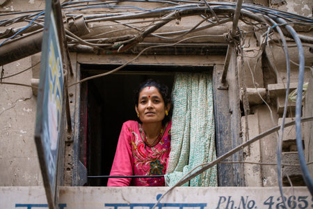 KATHMANDU, NEPAL - SEPTEMBER 28, 2016 : Nepalese woman looks out of a window to the street in...